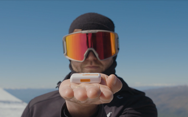 A skiier holds a wearable tech device in the palm of his hand